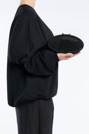Clutch indare nera, portata a mano dalla modella. TWENTYFOURHAITCH.