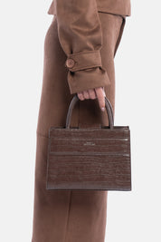 Mini tote bag serane marrone croco, portata a mano dalla modella. TWENTYFOURHAITCH.